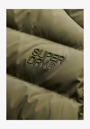 Oliwkowa kurtka puchowa z tkaniny o przeszytej strukturze. Zawiera wytłoczone logo „SUPERDRY” w dopasowanej zielonej nici. Gładka powierzchnia, lekki połysk.