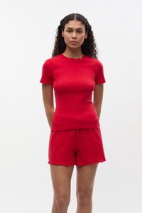 Conjunto de punto acanalado rojo que incluye una blusa ajustada de manga corta con un escote en picos y pantalones cortos a juego con cordón y dobladillo sin terminar.