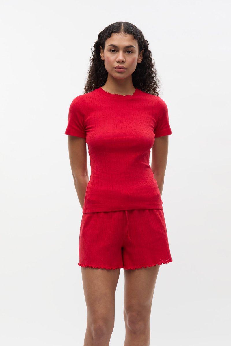 Completo a maglia a costine rossa composto da una maglietta aderente a maniche corte con scollatura ondulata e pantaloni corti abbinati con chiusura a cordino e orlo grezzo.