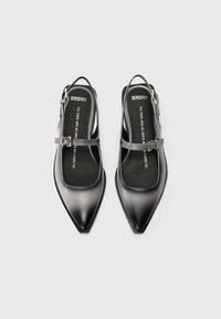 Black leather slingback shoes with a pointed toe, silver buckle accents, and a matte finish. Features a flat sole and open heel design.