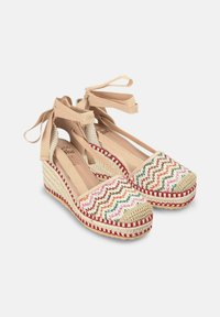 Alpargatas de cuña con patrón de chevron multicolor tejido, correas de tela beige y suela de yute texturizada; presentan costuras de acento rojas.