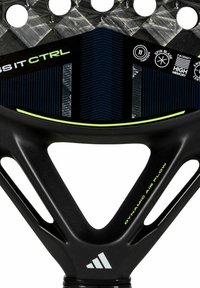 Black padel racket with a glossy finish, features a textured pattern, hexagonal holes, and lime green accents on the frame and logo details.