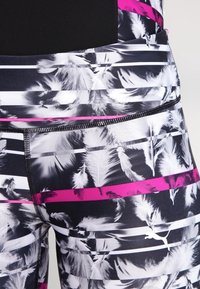 Leggings atletiche a vita alta con un motivo a piuma bianco e nero, accentuati da strisce rosa. Presentano una tasca posteriore sicura e un tessuto testurizzato.