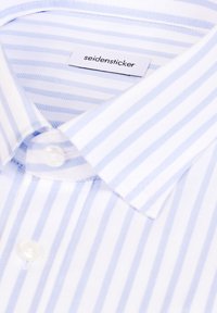 Koszula w jasnoniebiesko-białe paski, wykonana z bawełny, z kołnierzykiem na guziki, z małą metką "seidensticker" na karku.