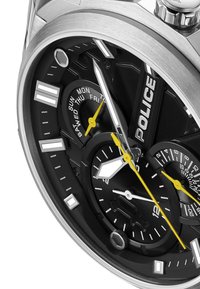 Ugotovite iz nerjavečega jekla z črnim številčnikom, srebrnimi detajli in rumenimi kazalci. Ima oznake za dan/datum ter teksturirano črno ozadje.