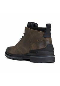 Bottine en cuir marron avec des accents noirs, bout rond, tige texturée et semelle robuste. Comprend des œillets et des détails de couture contrastants.