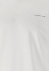 Valkoista kangasta lähikuvassa, jossa oikeassa yläkulmassa on pieniä, harmaita isoja kirjaimia käyttäen sana "ENDURANCE".