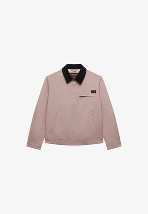 Chaqueta marrón claro con cremallera, cuello negro, bolsillo con cremallera en el pecho, dos bolsillos laterales y un pequeño parche rectangular en el pecho.