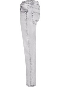 Jeans en denim gris clair avec une coupe slim, un design à cinq poches et une légère décoloration. Texture lisse avec une finition légèrement brillante.