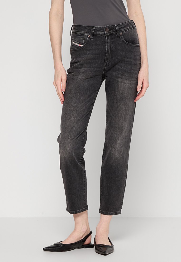 Czarne dżinsy o prostym kroju nogawki, pięć kieszeni i subtelne przetarcia; zestawione z czarnymi płaskimi butami.