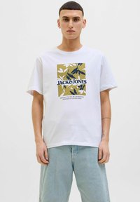 Hvid bomulds t-shirt med et rektangulært grafisk design med grønne og marineblå blade, mærkenavnet "JACK&JONES" i fed sort tekst.