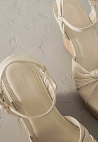Sandali con zeppa beige con dettaglio in tessuto arricciato, soletta imbottita e tacco in sughero texturizzato. Branding impresso all'interno.