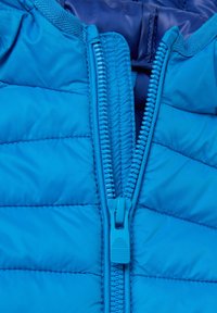 Padded blauer Anorak mit einem Frontreißverschluss, ausgestattet mit einem gesteppten Design und einem glatten Innenfutter. Der Reißverschlusszug ist ebenfalls blau mit strukturiertem Griff.