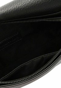 Interior de un bolso de cuero negro con superficie texturizada, cierre de cremallera y forro de tela suave. Cuenta con un compartimento lateral y una etiqueta.