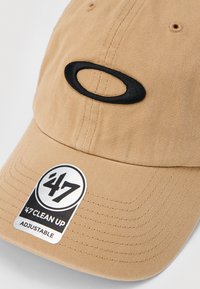 Beige színű, állítható baseball sapka, elöl fekete ovális logóval hímzéssel, és egy '47 Clean Up' matrica a hajlított ernyőn.