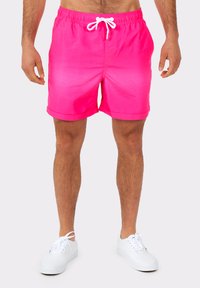 Bright pink swim shorts with a drawstring waist, a smooth texture, and rolled hems, paired with white canvas sneakers.