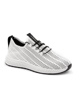 Baskets blanches en maille respirante avec lacets élastiques noirs, languette de talon noire et semelle blanche texturée, montrées sous un léger angle.