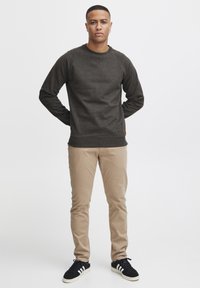 Donkergrijze sweatshirt met raglanmouwen, van een katoenmix, met ribgebreide boorden en zoom. In combinatie met beige slim-fit broeken en zwarte sneakers.