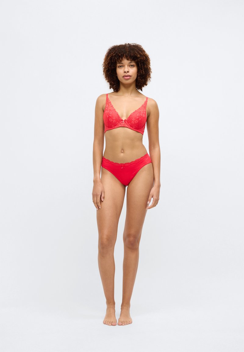 Soutien-gorge en dentelle rouge avec motif floral et décolleté en V, assorti à des culottes brésiliennes en dentelle rouge. Texture lisse, sans éléments métalliques visibles.