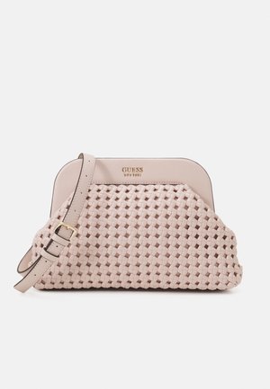 Sac à main Guess rose clair avec texture tissée, logo doré et bandoulière ajustable avec boucle sur fond blanc.
