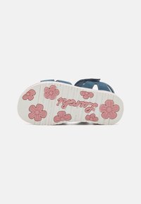 Sandalia de velcro con parte superior azul marino, suela de goma blanca con patrones florales en rosa y un diseño ergonómico para mayor comodidad.