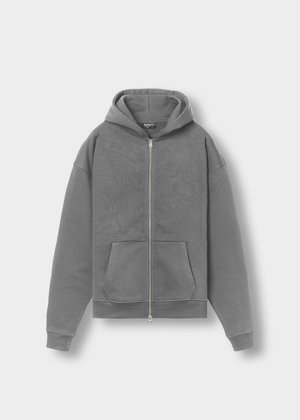 Felpa grigia con zip e cappuccio, tasche frontali e polsini a coste. Realizzata in morbido tessuto, presenta una leggera lucentezza e un discreto dettaglio con logo.