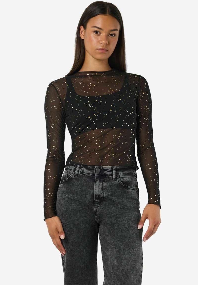 Črna prozorna majica z dolgimi rokavi in z zlatimi pikami; kvadratni izrez; v kompletu s hlačami iz sivo-jeans tkanine z visokim pasom. Gladka tekstura.