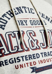 Hanorac gri cu text negru și bordo, având inscripțiile "AUTHENTIC DENIM" și "JACK & JONES." Include șnur și o textură moale.