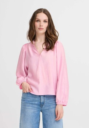 Light pink long-sleeve blouse with a V-neck and gathered, elastic cuffs, paired with blue denim, featuring a relaxed fit and soft texture.
