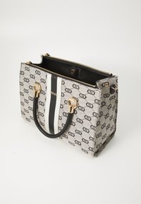 Canvas tote bag with a grey pattern, black and white stripe, gold hardware, and two black handles; zipper closure on top.