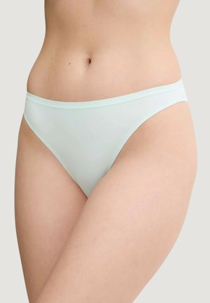 Torso femminile che indossa biancheria intima azzurra chiaro senza cuciture su uno sfondo chiaro, mostrando vita, fianchi e parte superiore delle cosce.