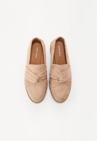 Pantofi slip-on din suede bej, cu detalii de bandă răsucită, margine cusută și talpă plată. Interiorul prezintă un căptușeală din material textil maro.