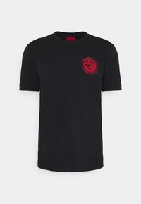 T-shirt en coton noir à manches courtes. Doté d'un imprimé graphique rouge sur la poitrine gauche, représentant un design de magasin de ramen avec du texte.