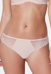 Sous-vêtements rose clair avec des détails en dentelle florale transparente et un corps en tissu lisse. Présente des accents brodés le long des bords et des coutures.