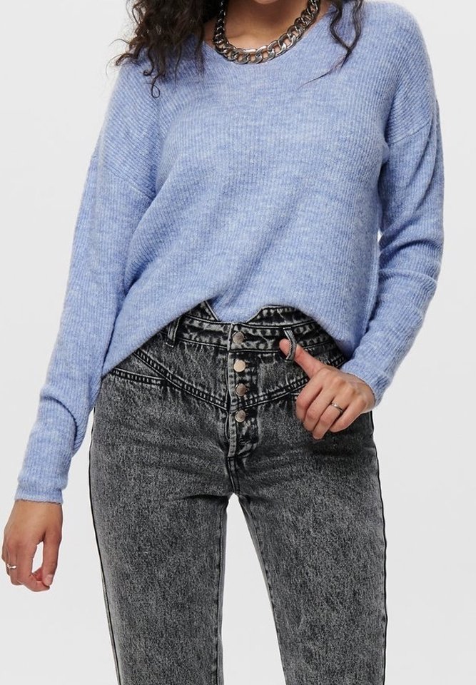 Femme portant un pull côtelé bleu clair rentré dans un jean noir taille haute délavé à l'acide avec fermeture à boutons et un collier chaînes.
