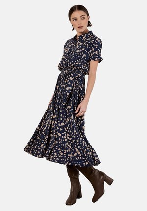 Marineblaues Midi-Kleid mit einem Button-Down-Kragen, kurzen Ärmeln, einem Gürtel in der Taille und einem geometrischen Muster in Beige. Glattes Material und ausgestellter Rock.