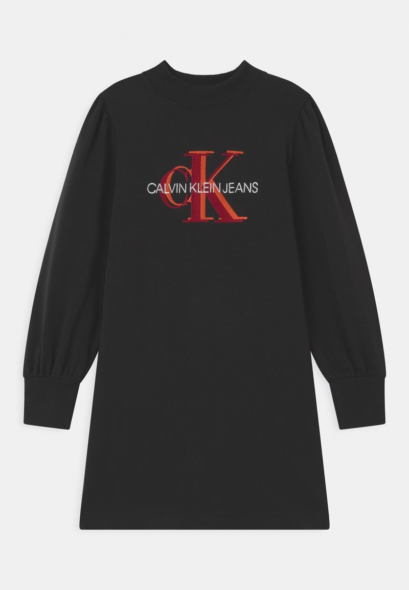 Svart bomullsklänning med långa, puffiga ärmar. Framsidan visar en röd och vit broderad logotyp: "CALVIN KLEIN JEANS" med stiliserad "CK."