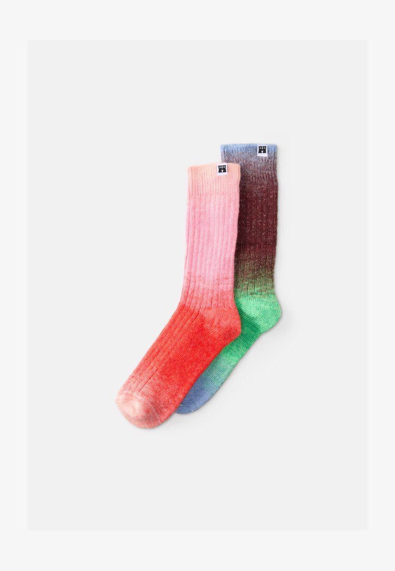 Calze lavorate a maglia che mostrano una sfumatura dal rosa al rosso e dal marrone al verde, con un texture a coste e bande di colore a contrasto in cima.