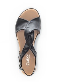 Sandale en cuir noir avec des sangles croisées, boucle ajustable et semelle intérieure rembourrée marron. Nom du fabricant visible sur la semelle.