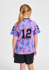 Kortärmad tröja i en rosa, blå och lila gradient med svarta detaljer. Har numret 12 och "LIGHT THE WORLD" i svart på baksidan.