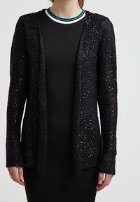Svart stickad cardigan med en lös passform, med paljetterade detaljer genom hela plagget, öppen framsida och långa ärmar. Mjuk textur och minimalistisk design.
