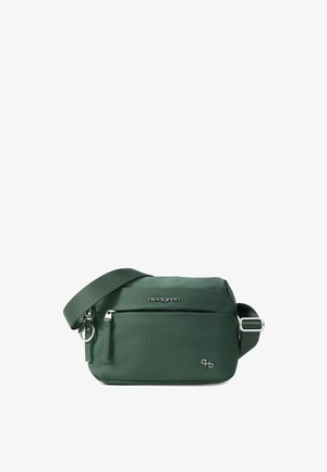 Sac bandoulière vert foncé avec sangle réglable, poche avant zippée et logo Hedgren en métal sur une surface en tissu lisse.