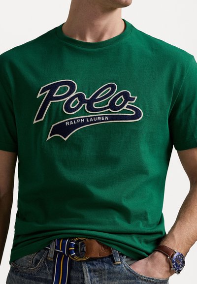 Πράσινο βαμβακερό t-shirt με λευκό και ναυτικό λογότυπο "Polo Ralph Lauren". Κοντά μανίκια, στρογγυλή λαιμόκοψη, λεία υφή. Συνδυάζεται με τζιν και καφέ ζώνη.