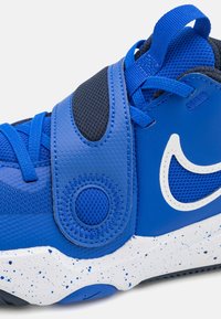 Niebieskie i czarne sneakersy Nike z rzepem, z siateczkowego materiału, białym logo w formie „swoosh” oraz białą, cętkowaną podeszwą.