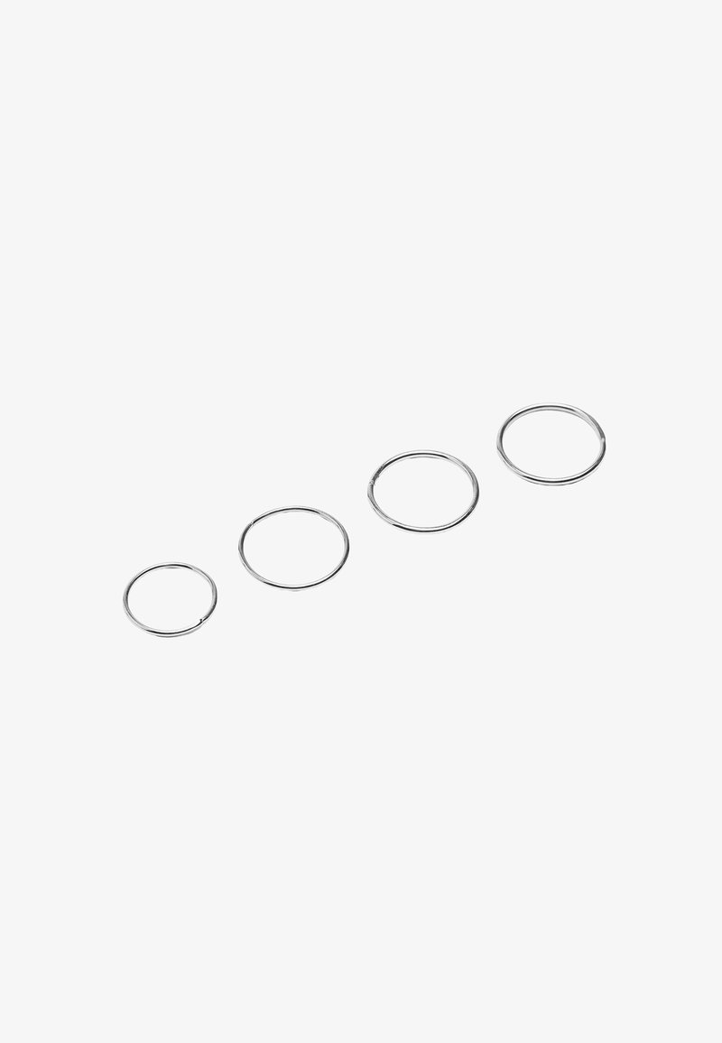 Cztery metalowe breloczki w różnych rozmiarach; błyszczące srebrne wykończenie, okrągły kształt, gładka tekstura, ułożone od najmniejszego do największego.