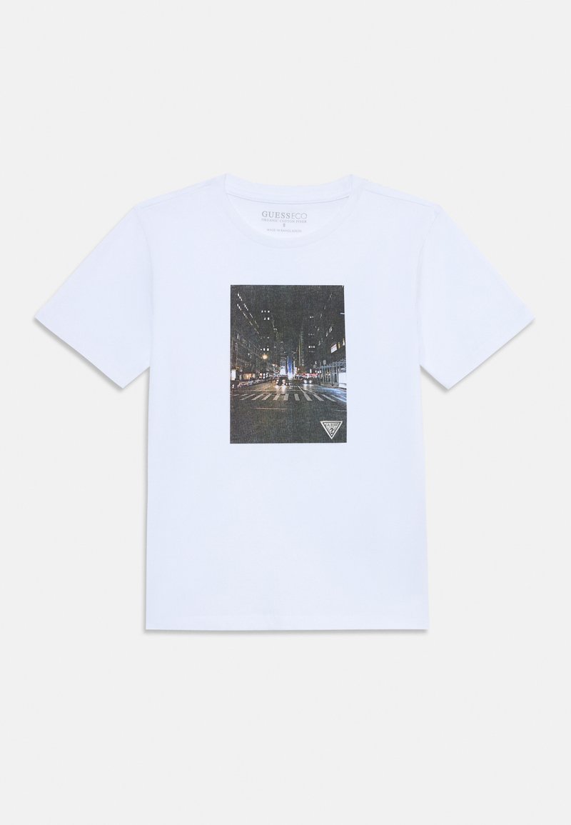 Λευκό βαμβακερό T-shirt με μια ορθογώνια γραφική εικόνα μιας σκηνής δρόμου της πόλης τη νύχτα, με ένα τριγωνικό λογότυπο στην κάτω γωνία.
