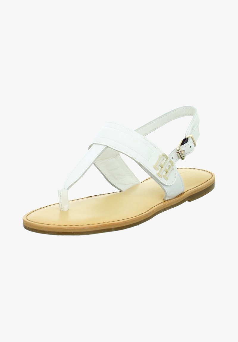 Sandale en cuir blanc à lanière avec semelle couleur tabac, bride de cheville réglable et détail du logo en métal doré sur le côté.