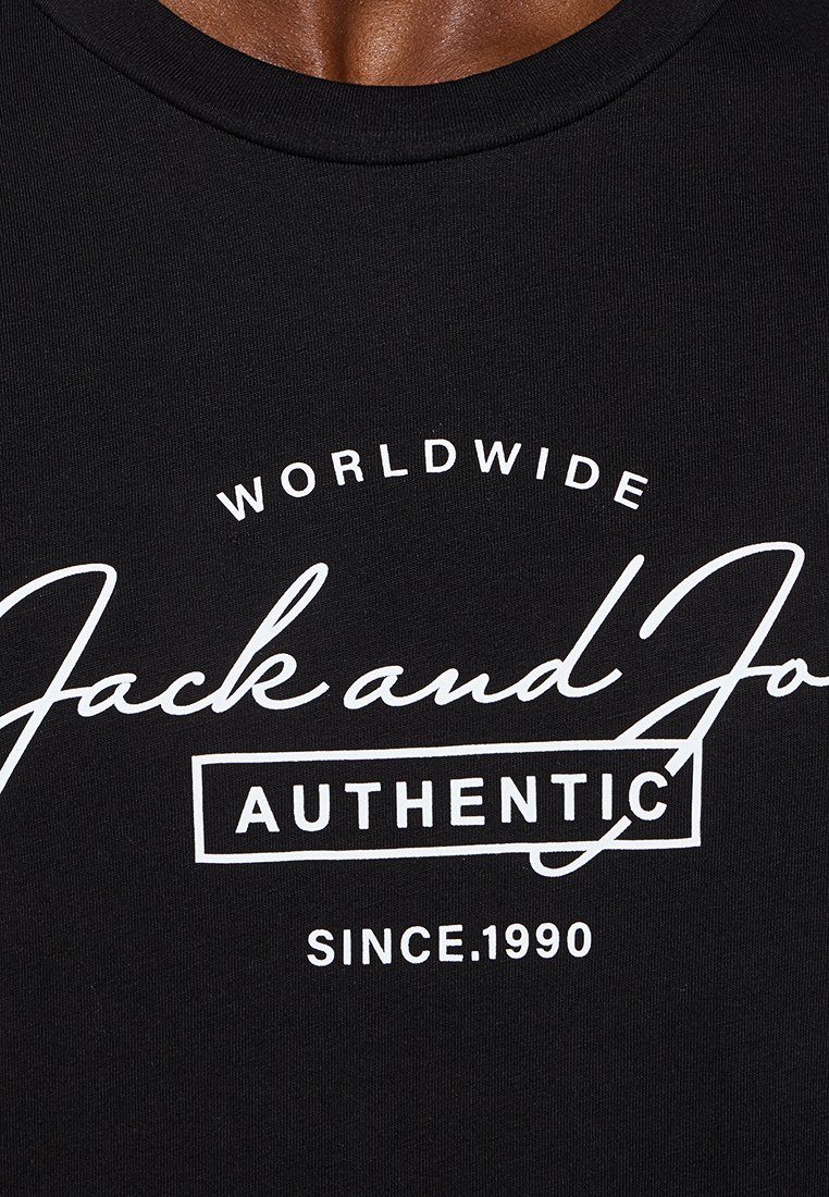 Schwarzes Rundhals-T-Shirt aus Baumwolle. Mit weißem grafischem Text: „WORLDWIDE Jack and Jones AUTHENTIC SINCE 1990“ in unterschiedlichen Stilen.