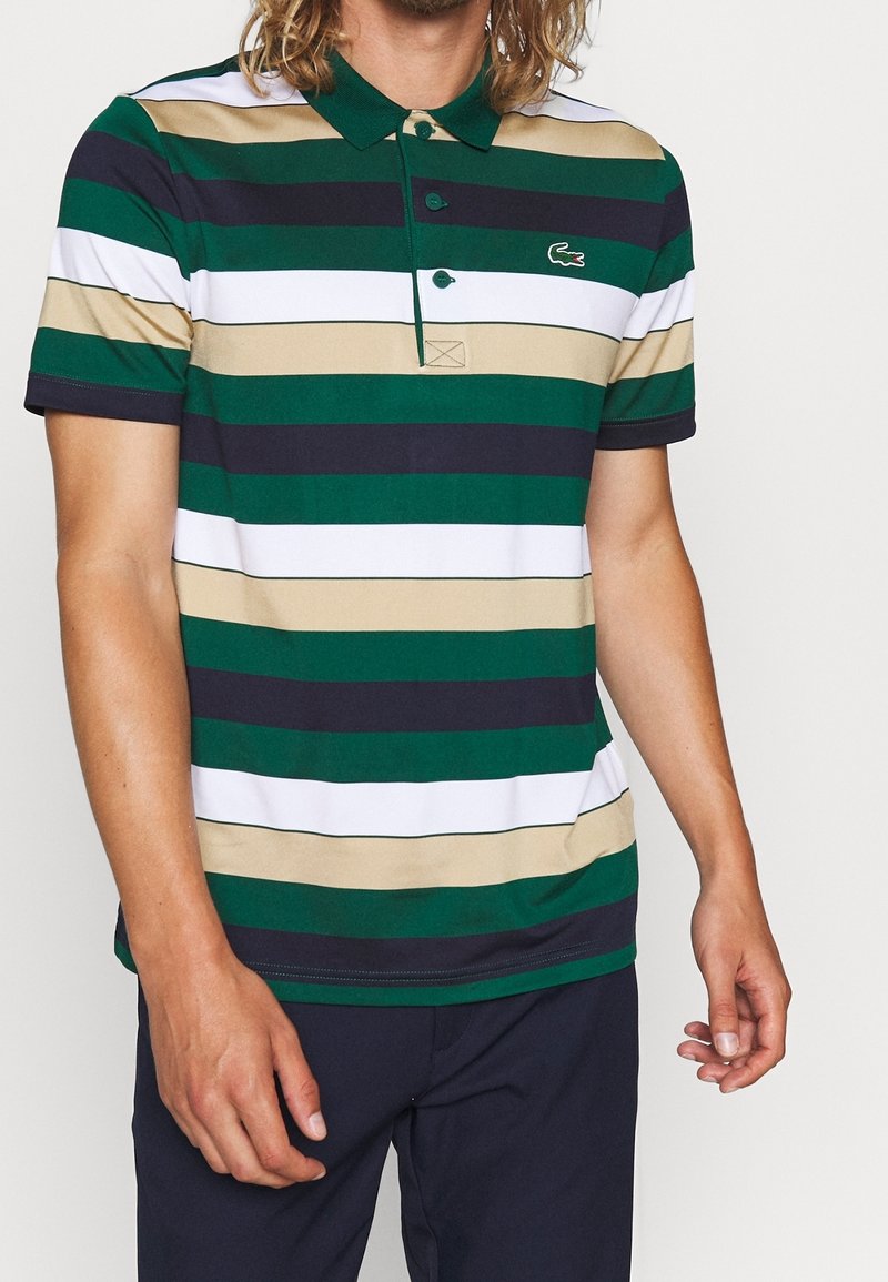 Pikétröja med horisontella ränder i grönt, marinblått, vitt och beige, med en klassisk krage och en liten broderad logotyp på bröstet.