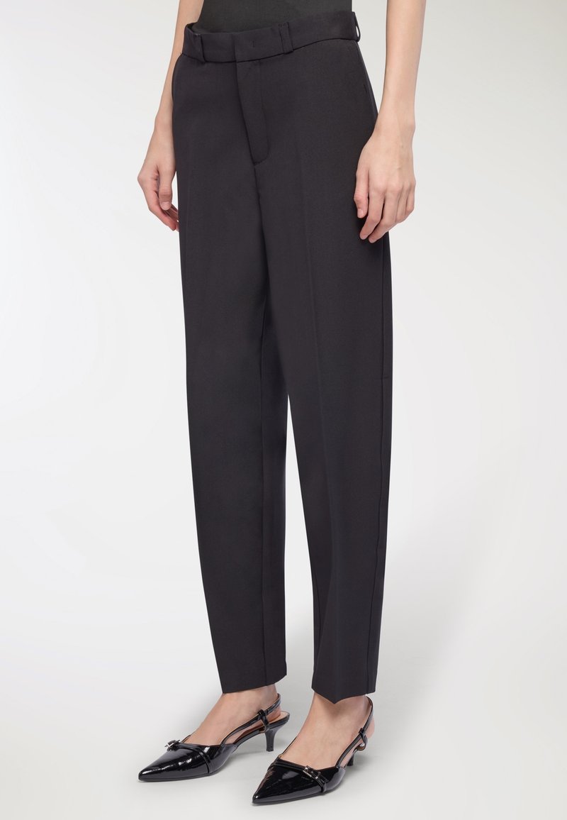 Czarne eleganckie spodnie z wysokim stanem i z paskiem, proste nogawki oraz subtelna tekstura. W zestawieniu z czarnymi lakierowanymi szpilkami z odkrytymi piętami.